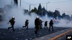 Polisi mengejar para demonstran dalam bentrokan di depan gedung parlemen di Athena (8/5). (AP/Yorgos Karahalis)