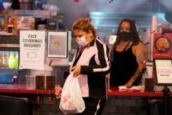 A customer picks up food at the Grand Central Market Monday, Nov. 16, 2020, in Los Angeles. California Gov. Gavin Newsom announced Monday, Nov. 16, 2020, that due to the rise of COVID-19 cases, Some counties have been moved to the state's most…