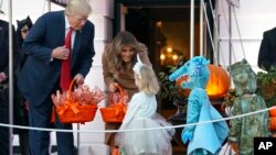 Presiden AS Donald Trump dan ibu negara Melania Trump membagikan permen kepada anak-anak dalam rangka perayaan Halloween di Gedung Putih, Senin (30/10).