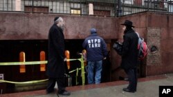 Members of the Lubavitch community watch a police officer enter Chabad-Lubavitch Hasidic headquarters in New York, Dec. 9, 2014.