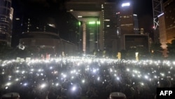 Para demonstran melambaikan ponsel dan alat elektronik lain saat melakukan protes pro-demokrasi di kompleks pemerintahan Hong Kong (31/8). (AFP/Alex Ogle) 