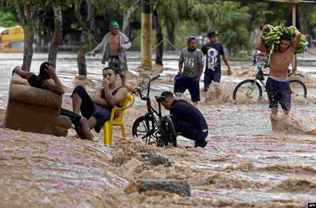 Seorang pria memanggul setandan pisang saat melewati jalanan yang tergenang banjir akibat badai tropis Iota di kota El Progreso, provinsi Yoro, Honduras.