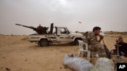 FILE - Libyan soldiers take a break from fighting with militants on the frontline in Al Ajaylat, 120 kilometers (75 miles) west of Tripoli, in this Feb. 21, 2015 photo.