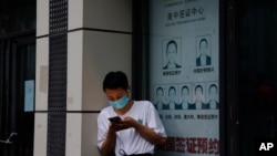 Čovjek stoji u blizini zatovrene radnje koja nudi usluge za apliciranje za vize, ispred Konzulata SAD u Čengdu, u jugozapadnoj kineskoj pokrajini Sečuan, 25. jula 2020.