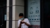 FILE - A resident wearing a mask to curb the spread of the coronavirus stands near a shuttered store that offered visa application services outside the U.S. Consulate in Chengdu in southwestern China's Sichuan province, July 25, 2020.