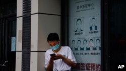 FILE - A resident wearing a mask to curb the spread of the coronavirus stands near a shuttered store that offered visa application services outside the U.S. Consulate in Chengdu in southwestern China's Sichuan province, July 25, 2020.