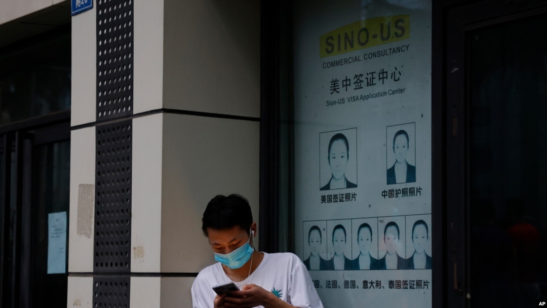 A resident wearing a mask to curb the spread of the coronavirus stand near a shuttered store that offered visa application services outside the United States Consulate in Chengdu in southwestern China's Sichuan province, July 25, 2020. 