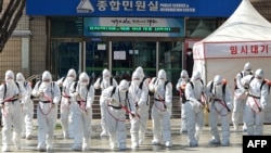 South Korean soldiers wearing protective gear spray disinfectant as part of preventive measures against the spread of the COVID-19 coronavirus, at city hall in Daegu on March 2, 2020. - South Korea confirmed 599 new coronavirus cases on March 2, taking th