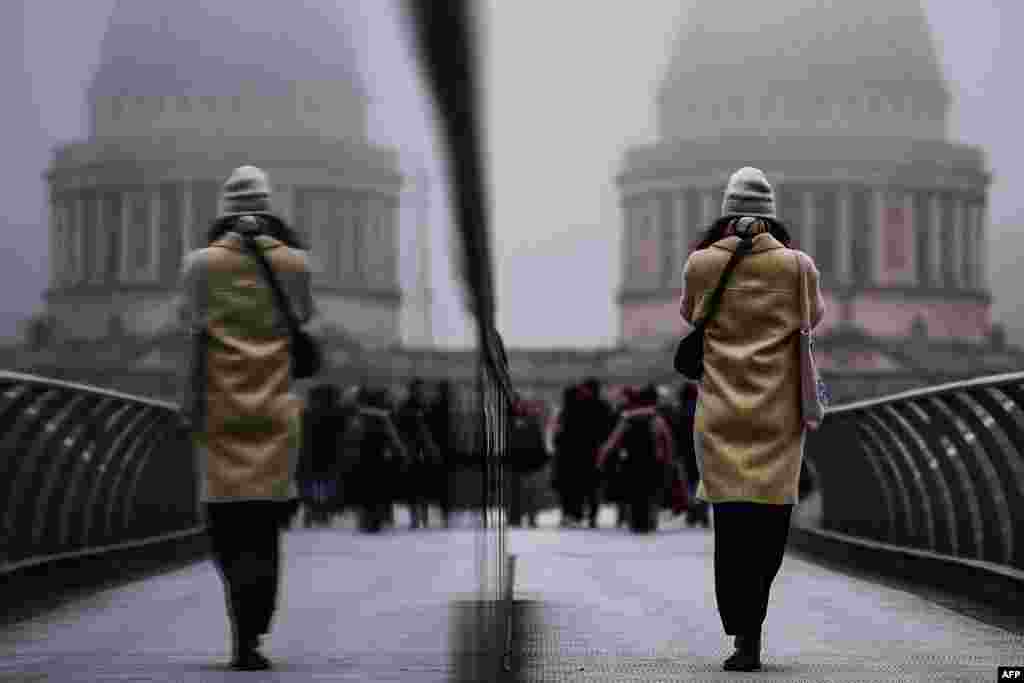 Pedestrians cross the Millennium Bridge during foggy weather in London.&nbsp;(Photo by HENRY NICHOLLS / AFP)