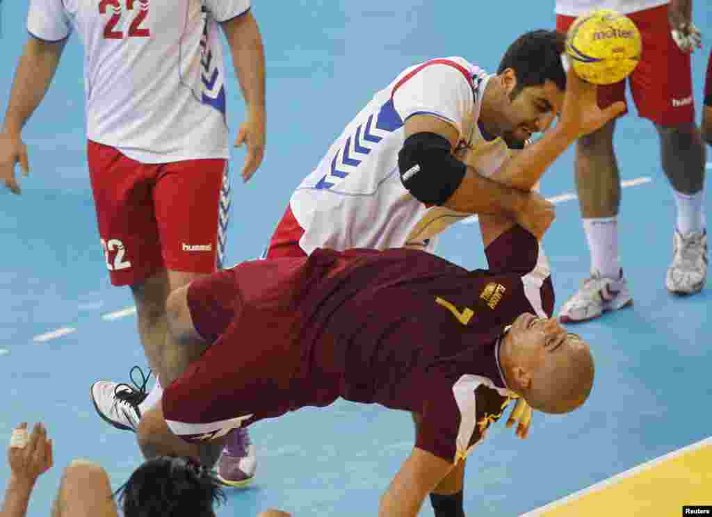 Mahmoud Osman of Qatar's Al-Jaish tries to score next to Meshari Alshammari (top) of Kuwait's Al Kuwait during the Asian handball club Championship in Doha November 4