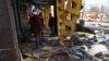 Orang-orang membantu membersihkan puing-puing di stasiun bus yang rusak setelah penembakan, di tengah serangan Rusia di Ukraina, di Kherson, Ukraina 21 Februari 2023. (Foto: REUTERS/Lisi Niesner)