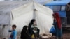 Internally displaced people sit outside tents at a makeshift camp in Azaz, Syria Feb. 19, 2020.