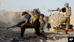 FILE - Iraqi security forces defend their positions against an Islamic State group attack in Husaybah, 8 kilometers (5 miles) east of Ramadi, Iraq, June 15, 2015. 