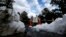 FILE - Freshly fallen snow is plowed into several piles, creating a barrier at the main entrance to Grand Canyon National Park, Oct. 10, 2013.