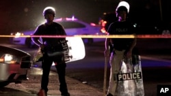 Police wearing riot gear stand at a post as they wait for a crowd to disperse in Ferguson, Missouri, Aug. 11, 2014.