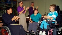 FILE - Judy Heumann, center, is applauded during her swearing-in as U.S. Assistant Secretary for Special Education and Rehabilitative Service by Judge Gail Bereola, left, in Berkeley, Calif., on Tuesday, June 29, 1993.