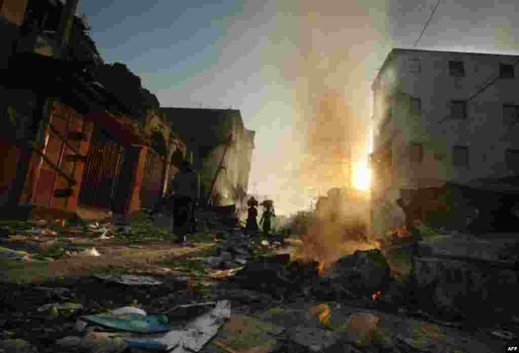 January 18: People walk through fire and rubble in the market area in Port-au-Prince, Haiti. (AP Photo/Gerald Herbert)