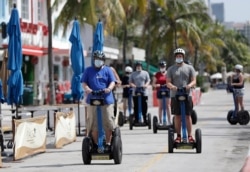 A tour group riding Segways rides down Miami Beach's famed Ocean Drive on South Beach, July 4, 2020. The Fourth of July holiday weekend began Saturday with Florida logging a record number of people testing positive for the coronavirus.