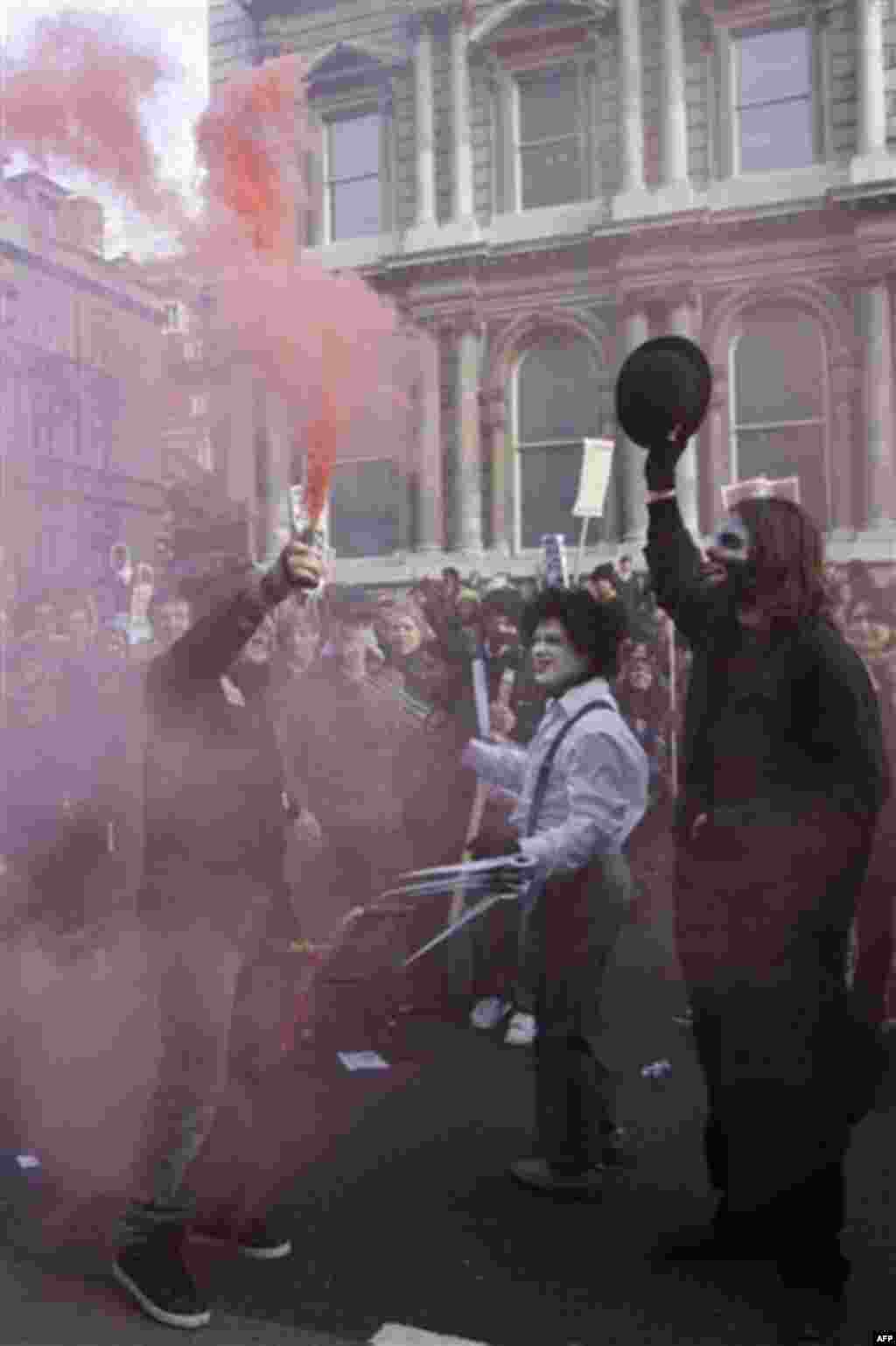 A protester holds up a smoke flare as thousands of student protest against tuition fees at Whitehall in London, Wednesday, Nov. 24, 2010. Thousands of British students protested Wednesday against government plans to triple tuition fees, two weeks after a 