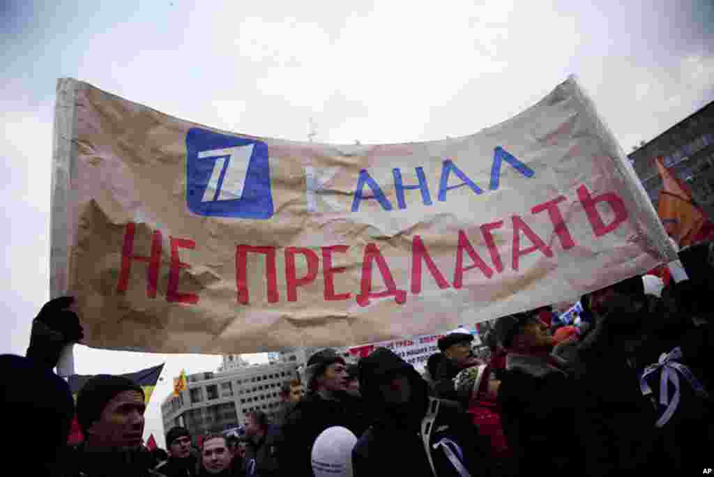 Protesters hold a sign that reads, "Don't offer us Channel One," a reference to the fact that protesters are turning to internet and digital cable for their news rather than state-run television, December 24, 2011. (VOA - Y. Weeks)