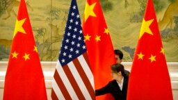 FILE - Chinese staffers adjust U.S. and Chinese flags before a session of negotiations between U.S. and Chinese trade representatives, at the Diaoyutai State Guesthouse, in Beijing, China, Feb. 14, 2019.