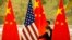 FILE - Staffers adjust Chinese and U.S. flags ahead of negotiations between Chinese and U.S. officials at the Diaoyutai State Guesthouse in Beijing, China, Feb. 14, 2019.