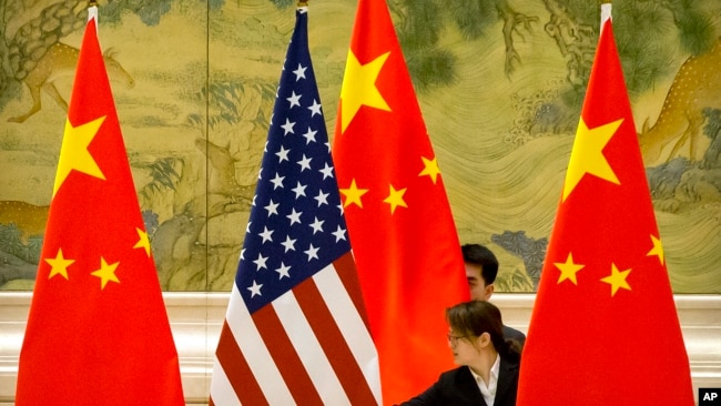 资料照片： 在北京钓鱼台国宾馆，中方工作人员在美中贸易谈判开始前摆放两国国旗.（2019年2月14日）