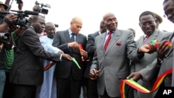 Senegalese President Abdoulaye Wade cuts the ribbon at the ceremony next to his son, State Minister for Air Transport Karim Wade