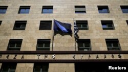 FILE - A European Union flag (L) flutters next to a Greek flag on the facade of the Bank of Greece headquarters in Athens, April 14, 2015.