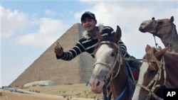 A guide looks for clients in front of the Sphinx and Giza Pyramids, Egypt, February 14, 2011