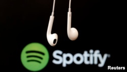 Earphone menggantung di depan logo layanan aliran musik Internet, Spotify.