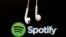 Earphone menggantung di depan logo layanan aliran musik Internet, Spotify.