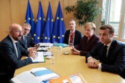 European Council President Charles Michel, left, speaks with French President Emmanuel Macron, right, and German Chancellor Angela Merkel, second right, during a meeting on the sidelines of an EU summit in Brussels, Belgium, Feb. 20, 2020.