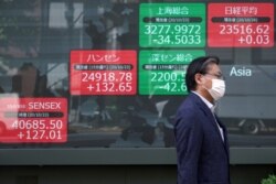 A man walks past an electronic stock board showing Japan's Nikkei 225 and other Asian indexes at a securities firm in Tokyo, Oct. 26, 2020.