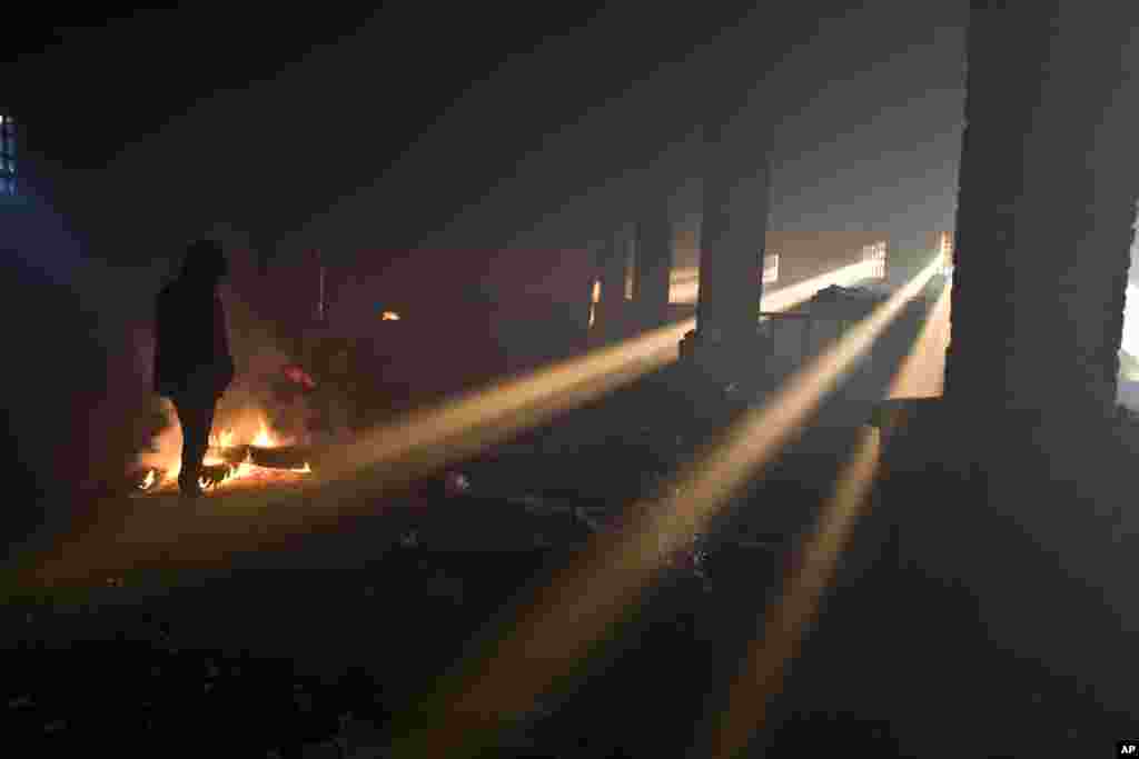 Migrants warm themselves around a fire in an abandoned warehouse in Belgrade, Serbia.