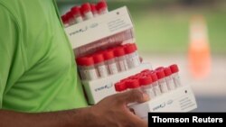 FILE PHOTO: Healthcare worker carries specimen collection tubes at COVID-19 drive-in testing location in Houston, Texas