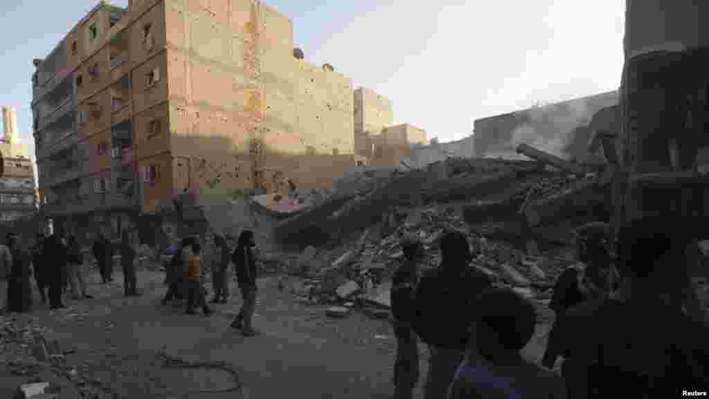 Civilians gather at a site of a collapsed building that activists said was shelled by forces loyal to Syria's President al-Assad in Deir al-Zor, October 14, 2013.