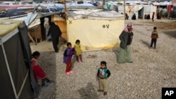 FILE - Syrian refugees, including children, stand outside their tents, in the town of Saadnayel, in the Bekaa valley, Lebanon, Jan. 22, 2016.