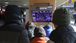 People watch a TV screen showing the news on a violent mob that loyal to U.S. President Donald Trump stormed the U.S. Capitol, at the Seoul Railway Station in Seoul, South Korea, Thursday, Jan. 7, 2021. (AP Photo/Ahn Young-joon)