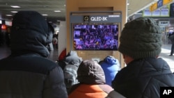 People watch a TV screen showing news coverage of a mob loyal to US President Donald Trump storming the US Capitol, at the Seoul Railway Station in Seoul, South Korea, Jan. 7, 2021.
