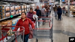 ARCHIVO - Consumidores esperan para pagar por sus compras en una tienda Costco en Los Ángeles, el 19 de febrero de 2025.