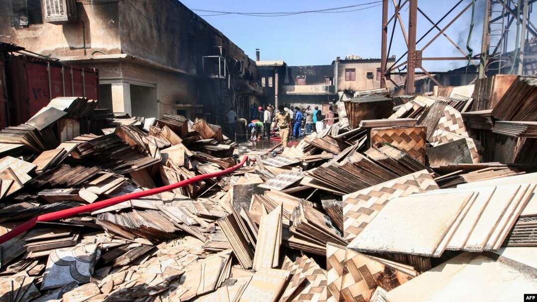 Warga dan petugas mencari korban di antara puing-puing pabrik yang terbakar di Khartoum, Selasa (3/12). 