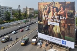 FILE - Indian commuters pass a poster of a Facebook ad campaign, in Bangalore, India, March 22, 2018.