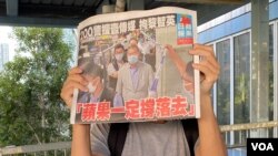 Warga menerima "Apple Daily" gratis pada tanggal 11 Agustus di luar Stasiun Kereta Api Tin Shui Wai Barat dan mengangkat halaman depan koran tersebut untuk menunjukkan dukungan mereka. (Photo: Tang Huiyun)
