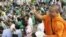 Venerable Loun Sovath sprinkles holly water to villagers who set a prayer rally to save rain forests in front of Royal Palace in Phnom Penh, Cambodia, Thursday, Aug. 18, 2011. Hundreds of villagers prayed at the spirit's shrine, demanding the governme