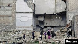 Children walk on the debris of a damaged building at al-Myassar neighborhood of Aleppo, Syria, Feb. 16, 2015.