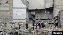 Children walk on the debris of a damaged building at al-Myassar neighborhood of Aleppo, Syria, Feb. 16, 2015.