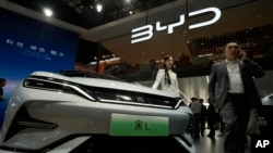 FILE - A model poses near the BYD Song L EV car during Auto China 2024 held in Beijing, April 25, 2024. 