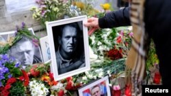 A woman places a portrait of late Russian opposition leader Alexey Navalny, who died unexpectedly in prison, on his memorial at Las Ramblas of Barcelona, in Barcelona, Spain, Feb. 25, 2024.