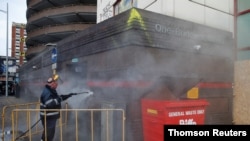 Workers clean up following anti-police bill protests in Bristol, England, that left several police officers injured and widespread damage to a police station, March 22, 2021.